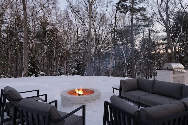 snow covered patio featuring an outdoor kitchen, grilling area, and an outdoor living space with a fire pit