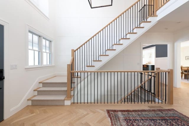 stairway with a decorative wall, a towering ceiling, and baseboards