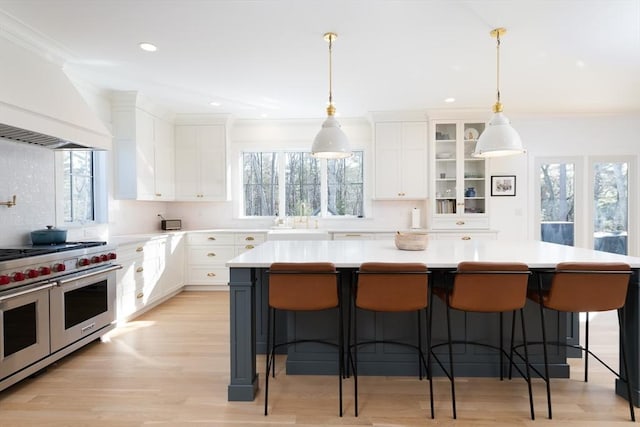 kitchen with premium range hood, a breakfast bar, double oven range, a center island, and glass insert cabinets