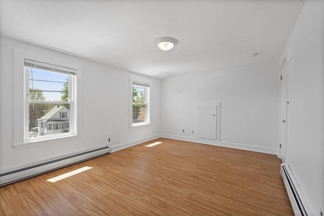 unfurnished room with a baseboard radiator, light wood-type flooring, and baseboards