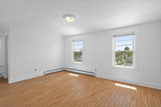 empty room with healthy amount of natural light, baseboard heating, wood finished floors, and baseboards