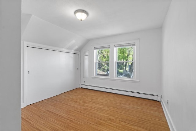 bonus room with a baseboard heating unit, lofted ceiling, and wood finished floors