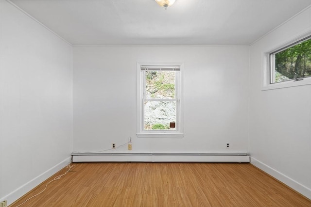empty room with baseboard heating, light wood-style flooring, baseboards, and crown molding