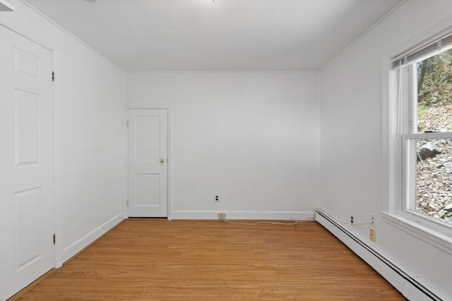 unfurnished room with a baseboard heating unit, light wood finished floors, baseboards, and ornamental molding