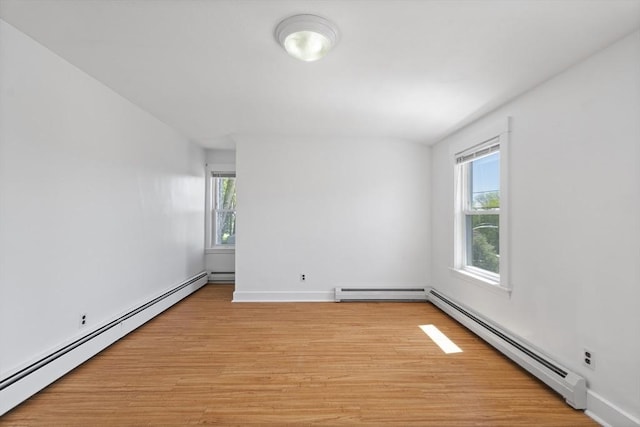 empty room featuring baseboard heating, light wood-style flooring, and baseboards