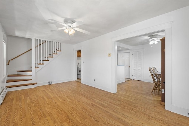 unfurnished living room featuring a ceiling fan, light wood-type flooring, stairs, and baseboards
