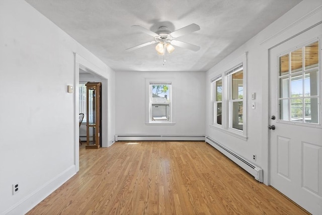 empty room with a baseboard radiator, light wood-style floors, ceiling fan, and a baseboard heating unit