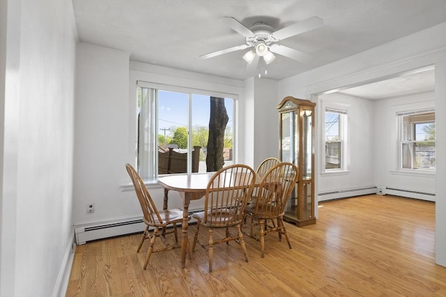 dining area with light wood-type flooring, a baseboard radiator, a ceiling fan, and baseboards