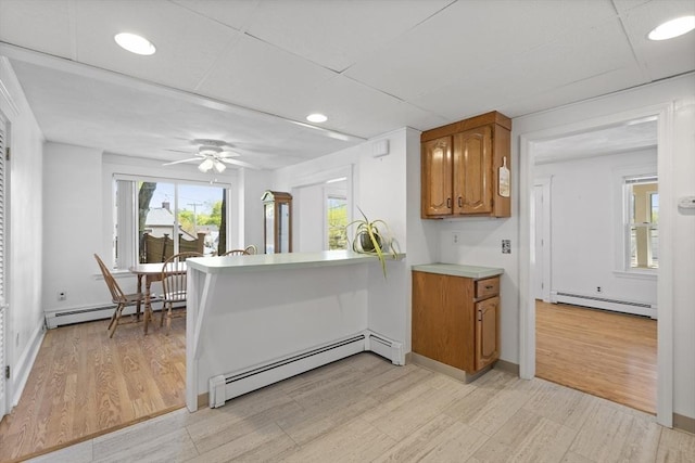 kitchen with a baseboard radiator, brown cabinets, light countertops, a peninsula, and recessed lighting