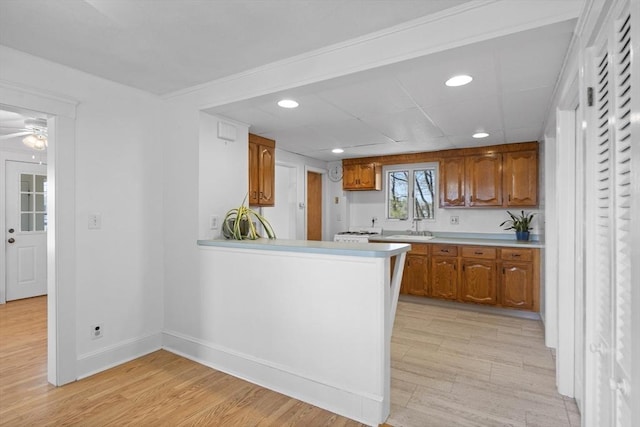 kitchen with brown cabinets, recessed lighting, light countertops, light wood-style floors, and baseboards