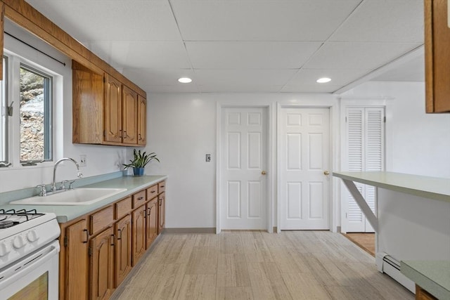 kitchen with brown cabinets, a sink, light countertops, recessed lighting, and light wood finished floors