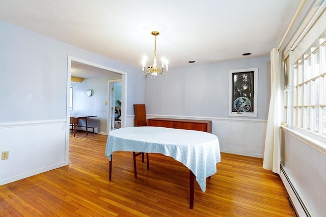 dining area with a chandelier, light wood-type flooring, and a baseboard heating unit