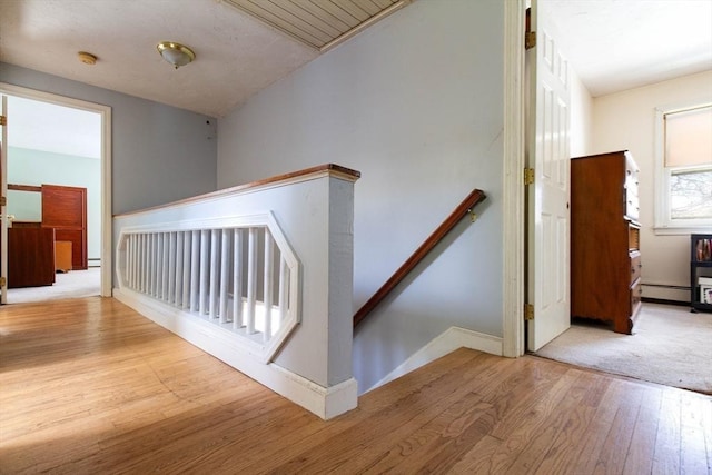 stairway with wood-type flooring and a baseboard radiator