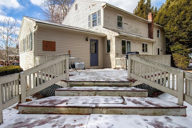 snow covered rear of property featuring a deck