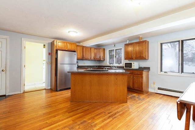 kitchen featuring sink, stainless steel fridge, a baseboard heating unit, a center island, and light hardwood / wood-style floors