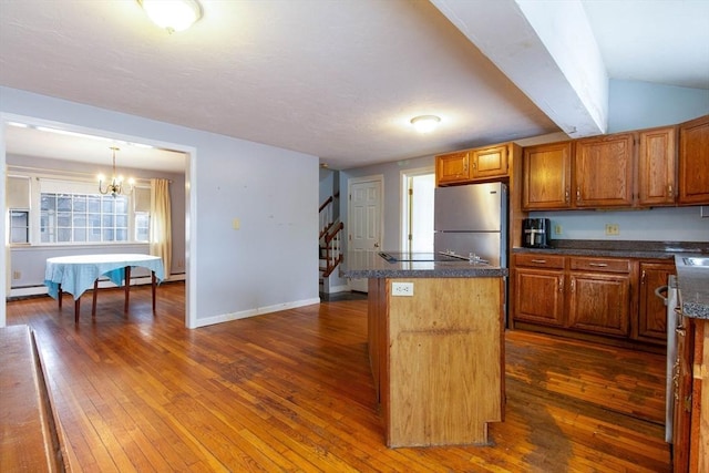 kitchen with a kitchen island, stainless steel refrigerator, decorative light fixtures, dark hardwood / wood-style flooring, and baseboard heating