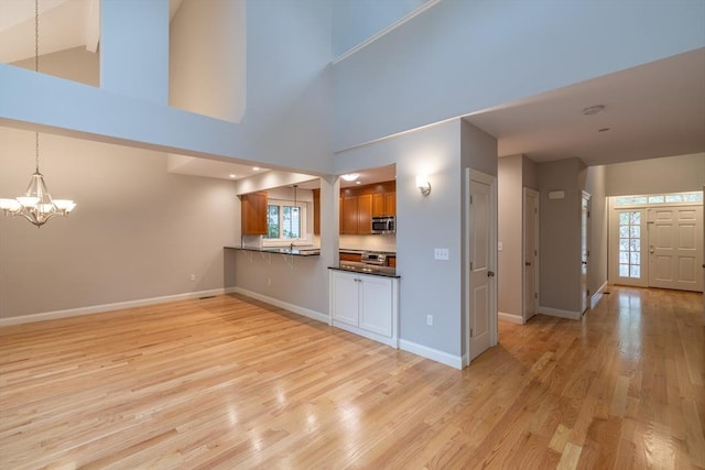 108 Johnson Woods Unit 108, Reading, MA 01867 - unfurnished living room featuring a chandelier, light wood-type flooring, and high vaulted ceiling