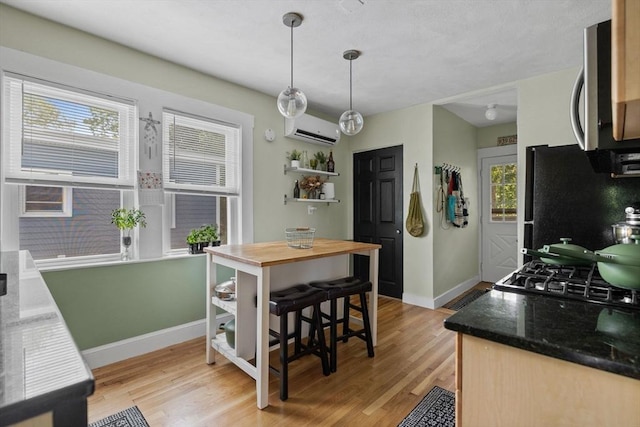 63-65 Brookley Rd Unit 3, Boston, MA 02130 - kitchen with stainless steel microwave, a wall mounted air conditioner, freestanding refrigerator, and light wood-style floors