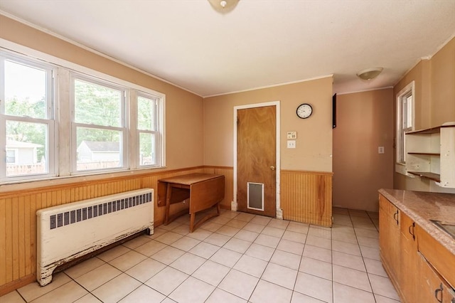 164 Leonard St, Agawam, MA 01001 - unfurnished dining area with radiator, a wainscoted wall, wood walls, crown molding, and light tile patterned floors