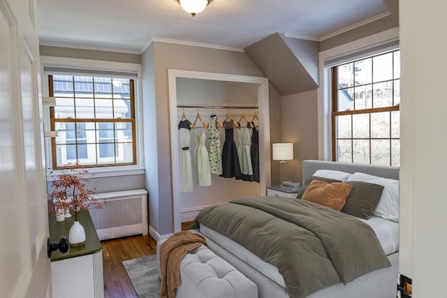 bedroom featuring dark hardwood / wood-style flooring, crown molding, multiple windows, and a closet