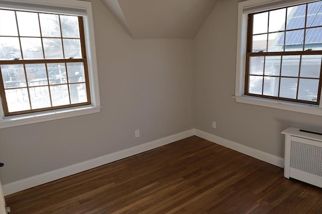 bonus room with lofted ceiling, dark wood-type flooring, and radiator heating unit