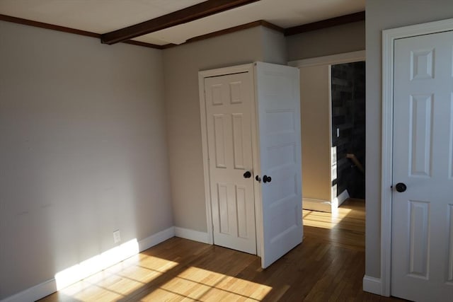 unfurnished bedroom with beam ceiling and hardwood / wood-style floors