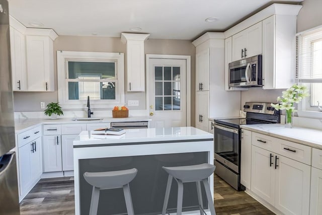 kitchen with white cabinetry, appliances with stainless steel finishes, sink, and a breakfast bar