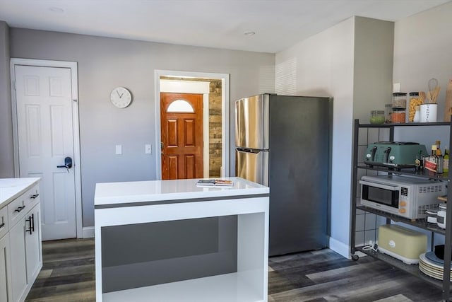 kitchen with white cabinetry, a center island, dark hardwood / wood-style floors, and stainless steel refrigerator