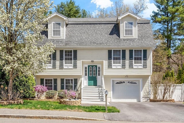 split foyer home featuring fence, roof with shingles, entry steps, an attached garage, and driveway