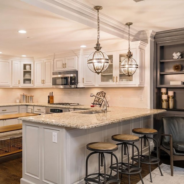 kitchen featuring a sink, a peninsula, white cabinetry, and stainless steel appliances