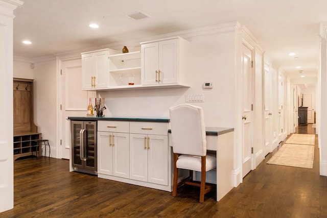 bar with ornamental molding, dark wood-style floors, built in desk, recessed lighting, and wine cooler