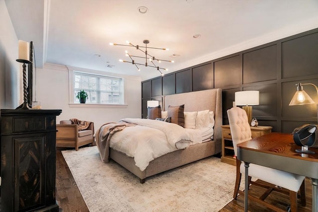 bedroom featuring an inviting chandelier, wood finished floors, and a decorative wall