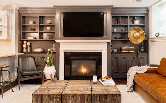 living area with visible vents, light wood-style floors, and a glass covered fireplace