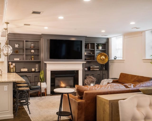 living area featuring dark wood finished floors, a fireplace with flush hearth, recessed lighting, and visible vents