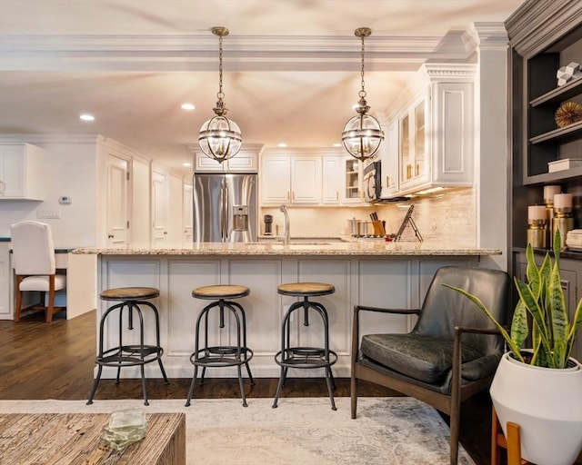 kitchen featuring a sink, light stone counters, a peninsula, and stainless steel fridge with ice dispenser