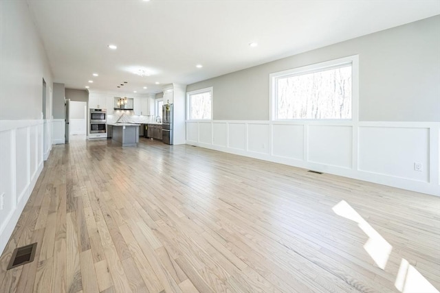 1 Falcon Dr, Shrewsbury, MA 01545 - unfurnished living room featuring a decorative wall, a wainscoted wall, light wood finished floors, and recessed lighting