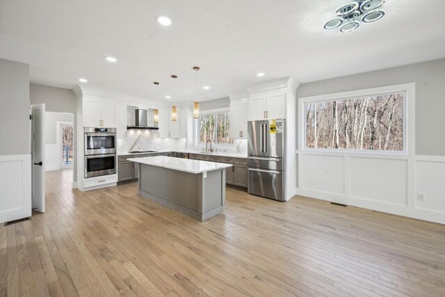 1 Falcon Dr, Shrewsbury, MA 01545 - kitchen with appliances with stainless steel finishes, wall chimney range hood, a decorative wall, light countertops, and a kitchen island
