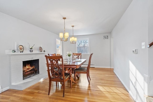 dining room with a fireplace, light hardwood / wood-style floors, a chandelier, and baseboard heating