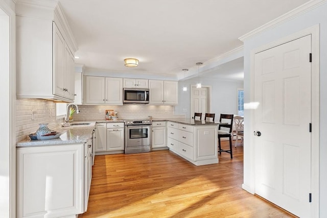 kitchen with tasteful backsplash, decorative light fixtures, kitchen peninsula, stainless steel appliances, and white cabinets