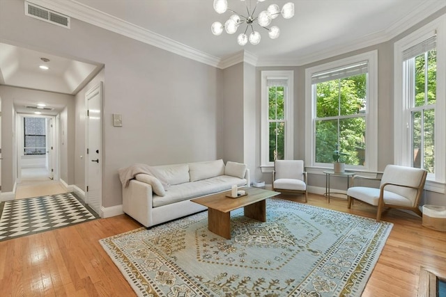 living area with a notable chandelier, baseboards, ornamental molding, visible vents, and wood finished floors