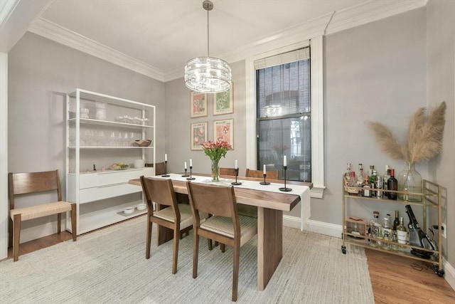 dining space with light wood-style floors, a chandelier, baseboards, and ornamental molding