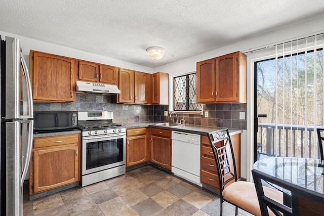 kitchen featuring appliances with stainless steel finishes, a textured ceiling, sink, and decorative backsplash