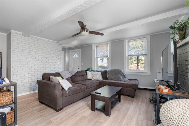 living area featuring crown molding, brick wall, baseboards, ceiling fan, and light wood finished floors