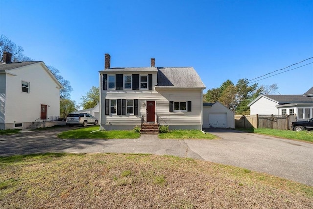 view of front of home with a garage, aphalt driveway, fence, a front yard, and a chimney