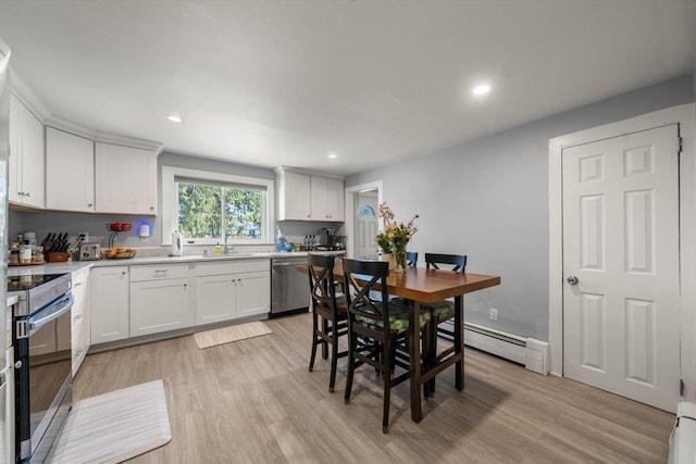 kitchen featuring appliances with stainless steel finishes, white cabinetry, light countertops, a baseboard heating unit, and light wood-style flooring