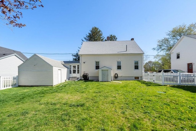 back of property featuring an outdoor structure, a yard, fence, and a storage shed