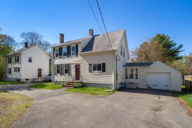 view of front of home with driveway, a chimney, and roof with shingles