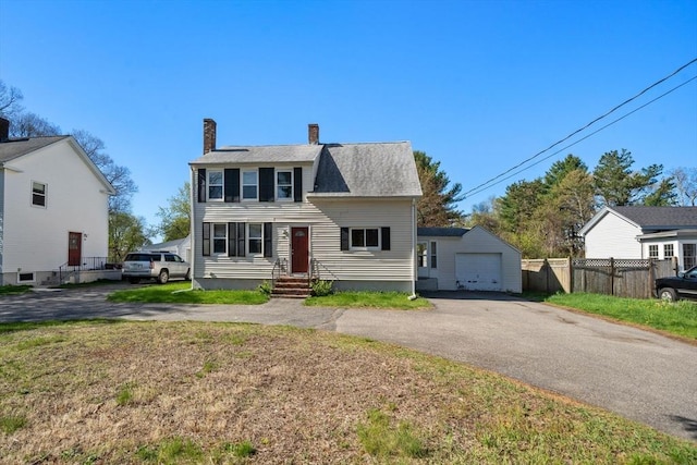 view of front of house featuring a chimney, a garage, fence, an outdoor structure, and aphalt driveway