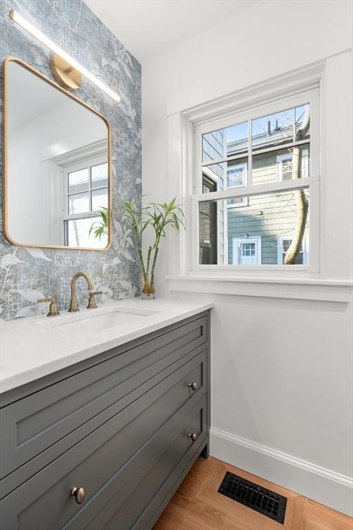 bathroom with baseboards, visible vents, wood finished floors, and vanity