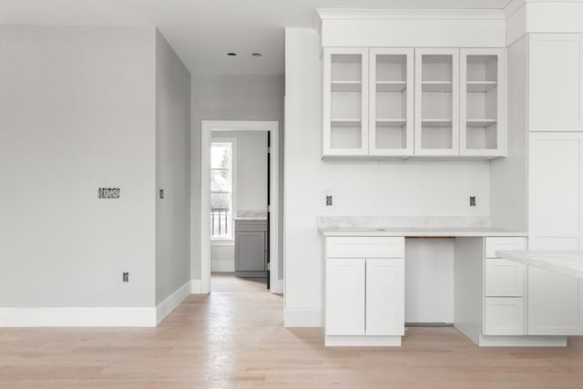 kitchen featuring glass insert cabinets, light countertops, white cabinetry, and light wood-style floors